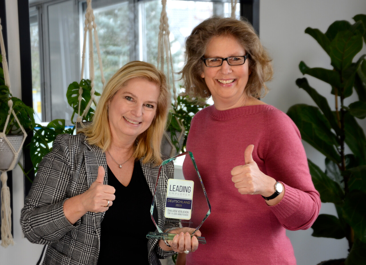 HR Officer and CEO presenting the glass trophy, smiling with thumbs up